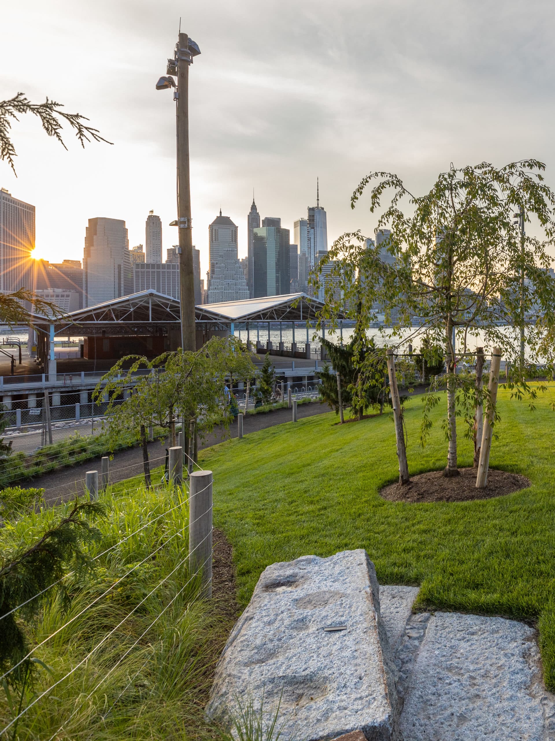 Pier 2 Uplands lawn with view of Pier 2 and lower Manhattan at sunset.