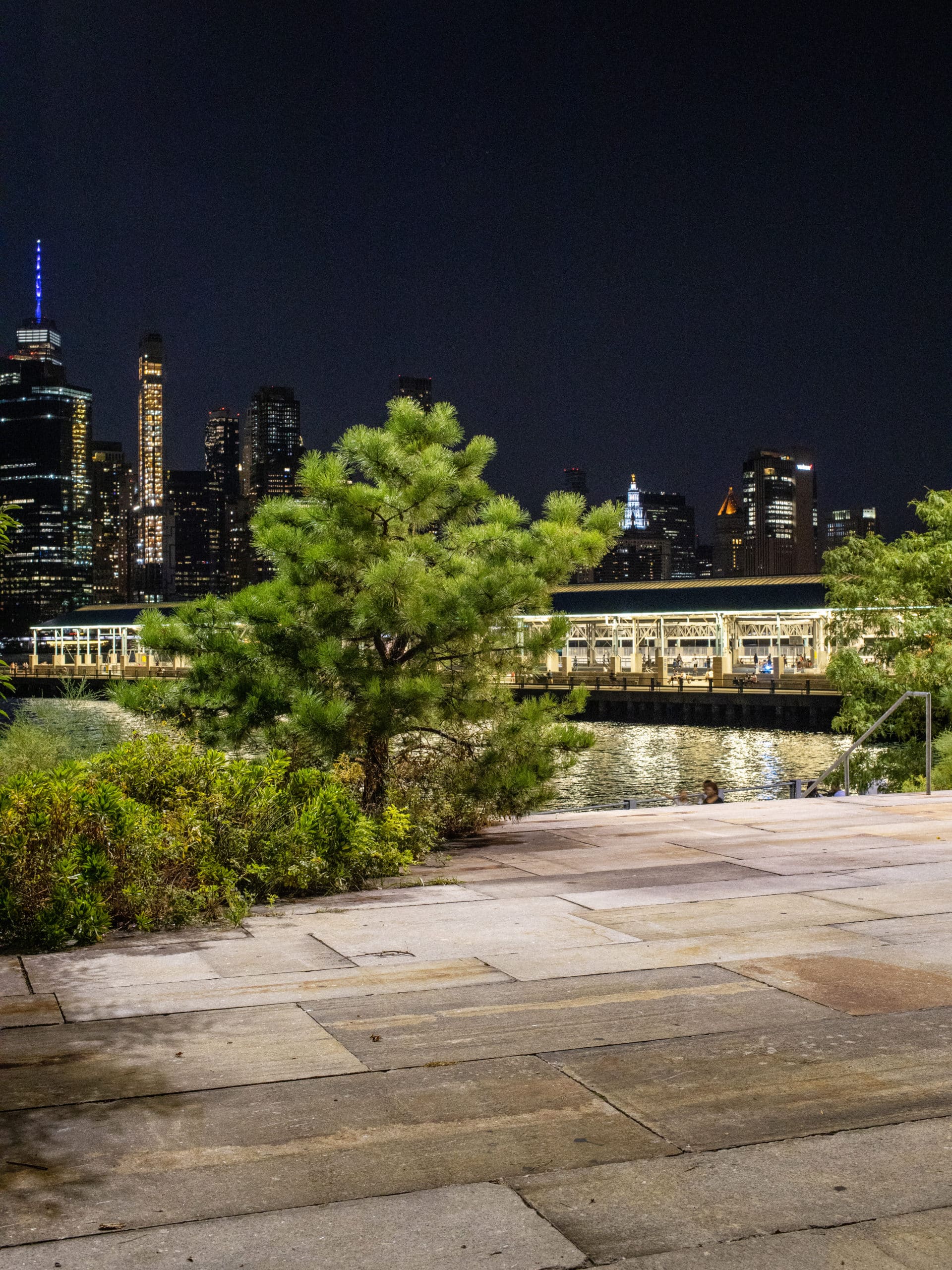 Pier 3 Greenway's Granite Terrace at night with a view of Pier 2 and lower Manhattan.