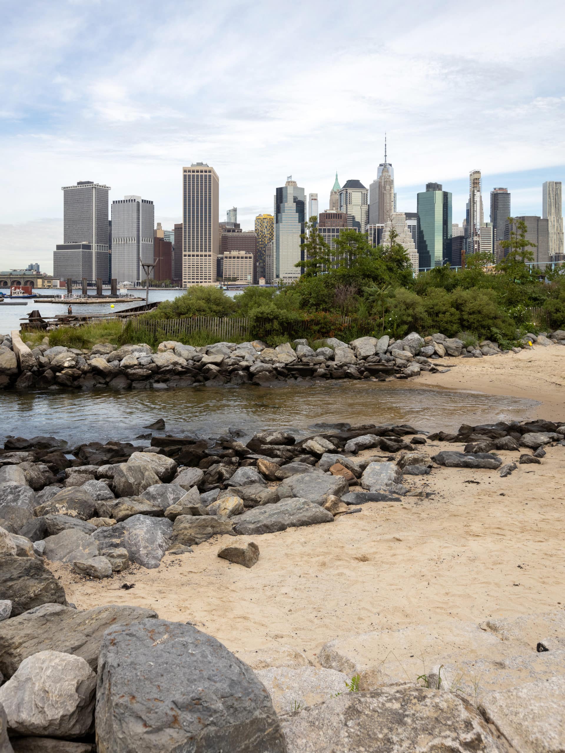 Rocks and trees along the Pier 4 Beach with lower Manhattan in the background.