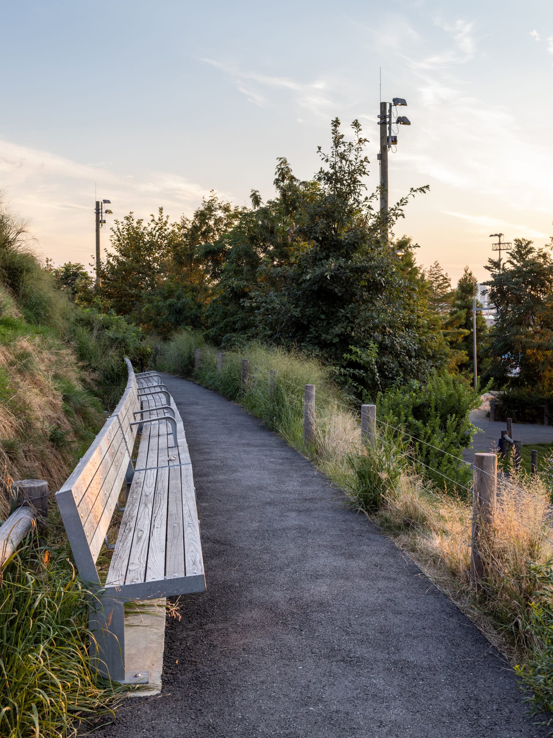 Benches along the pathway on Pier 5 Uplands Sound Attenuating Berm at sunset.