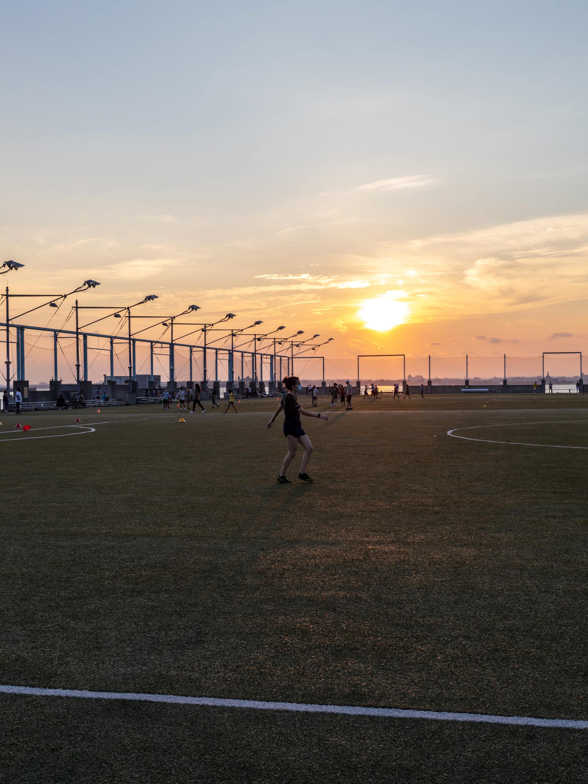 Woman exercising on Sport Fields at Pier 5 at sunset.