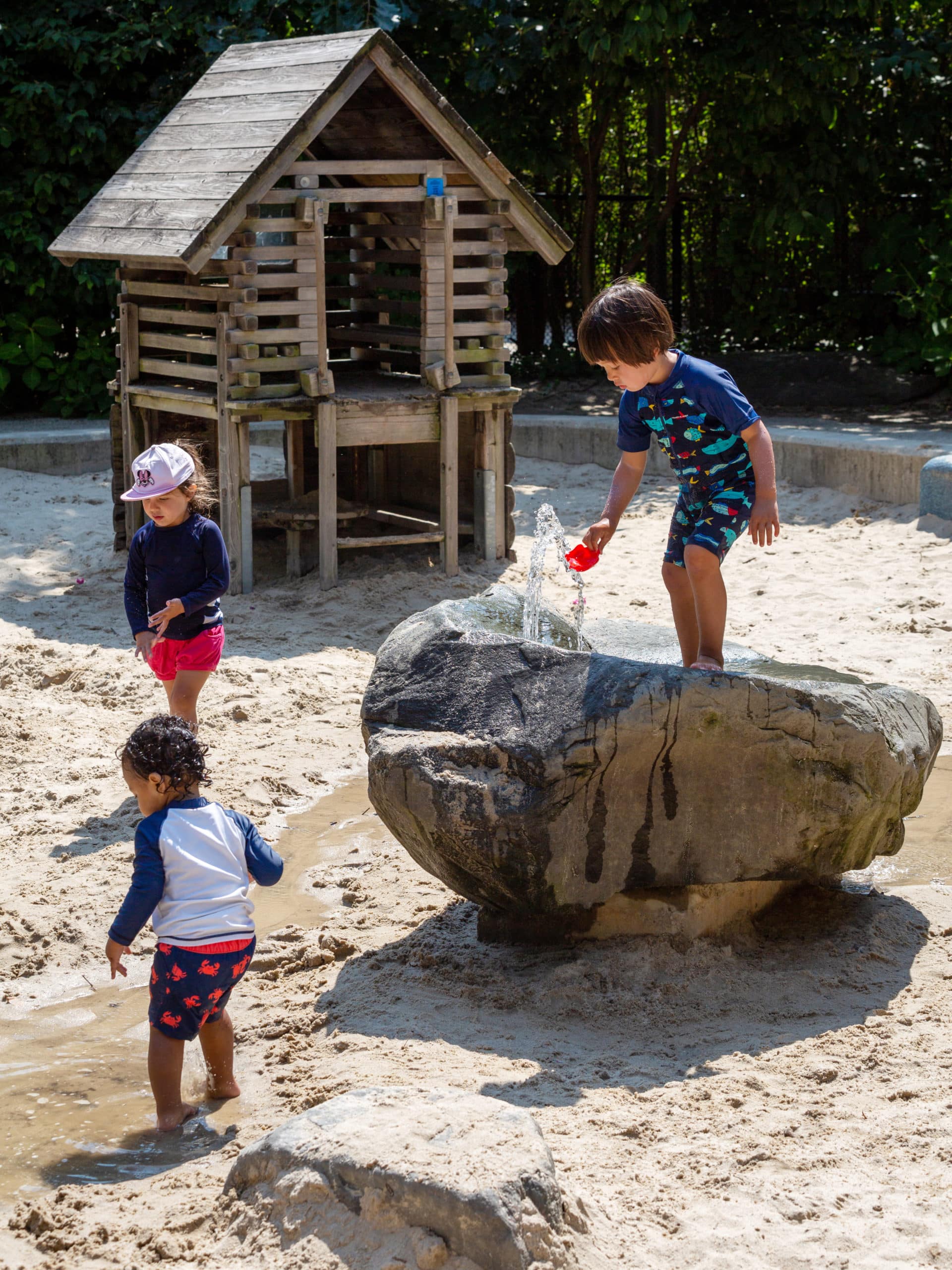 Small children playing with water in the sand pit at Sandbox Village in Pier 6 on a sunny day.