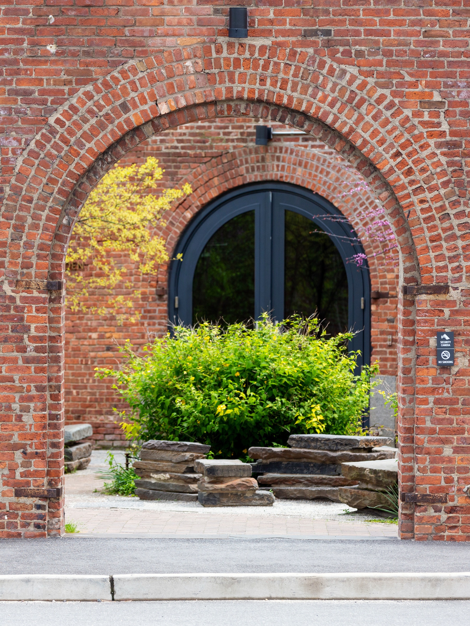 Bush and stone seating seen through brick archway in Max Family Garden.