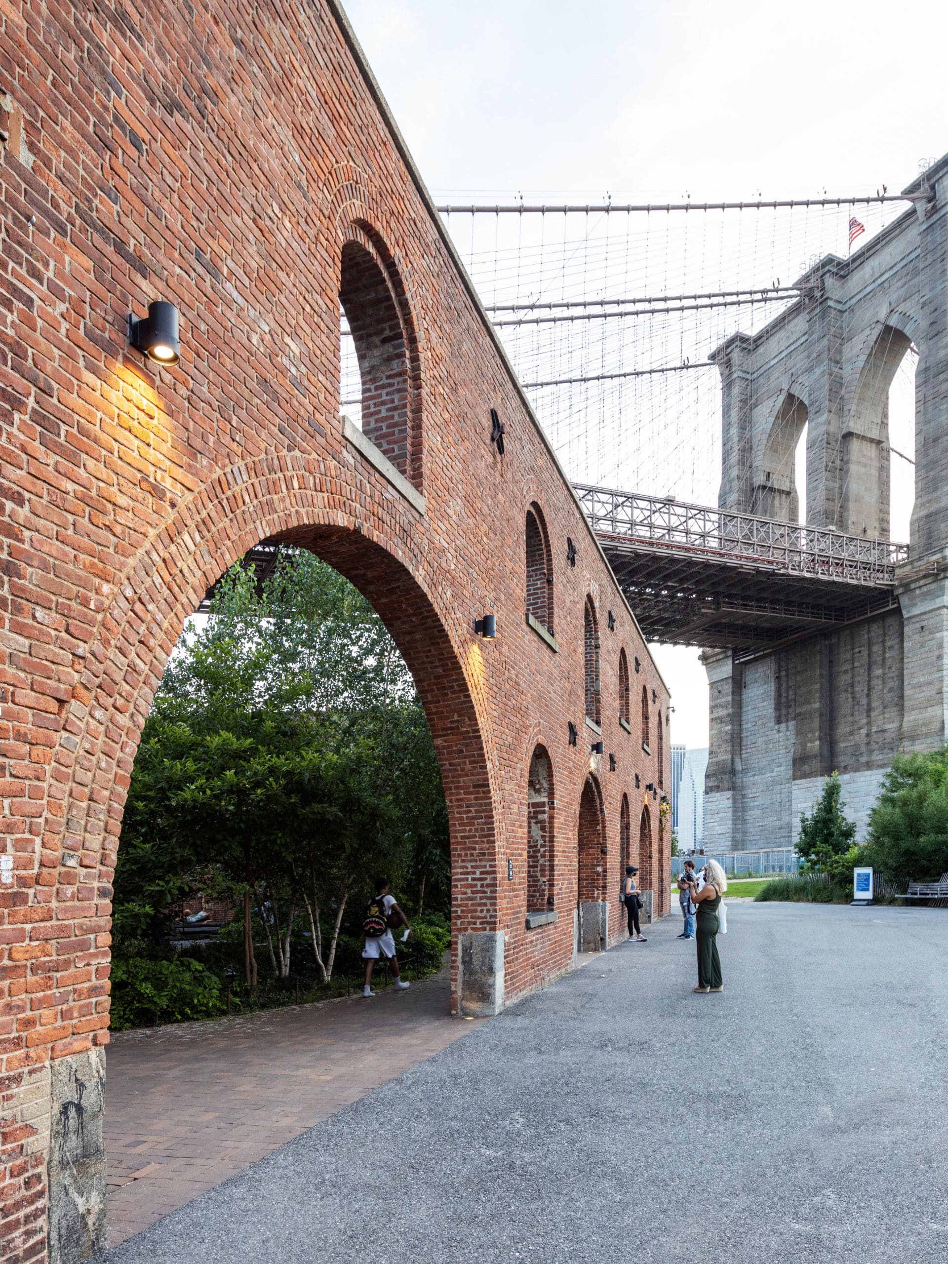 Arched brick entrance to Max Family Garden with Brooklyn Bridge overhead.