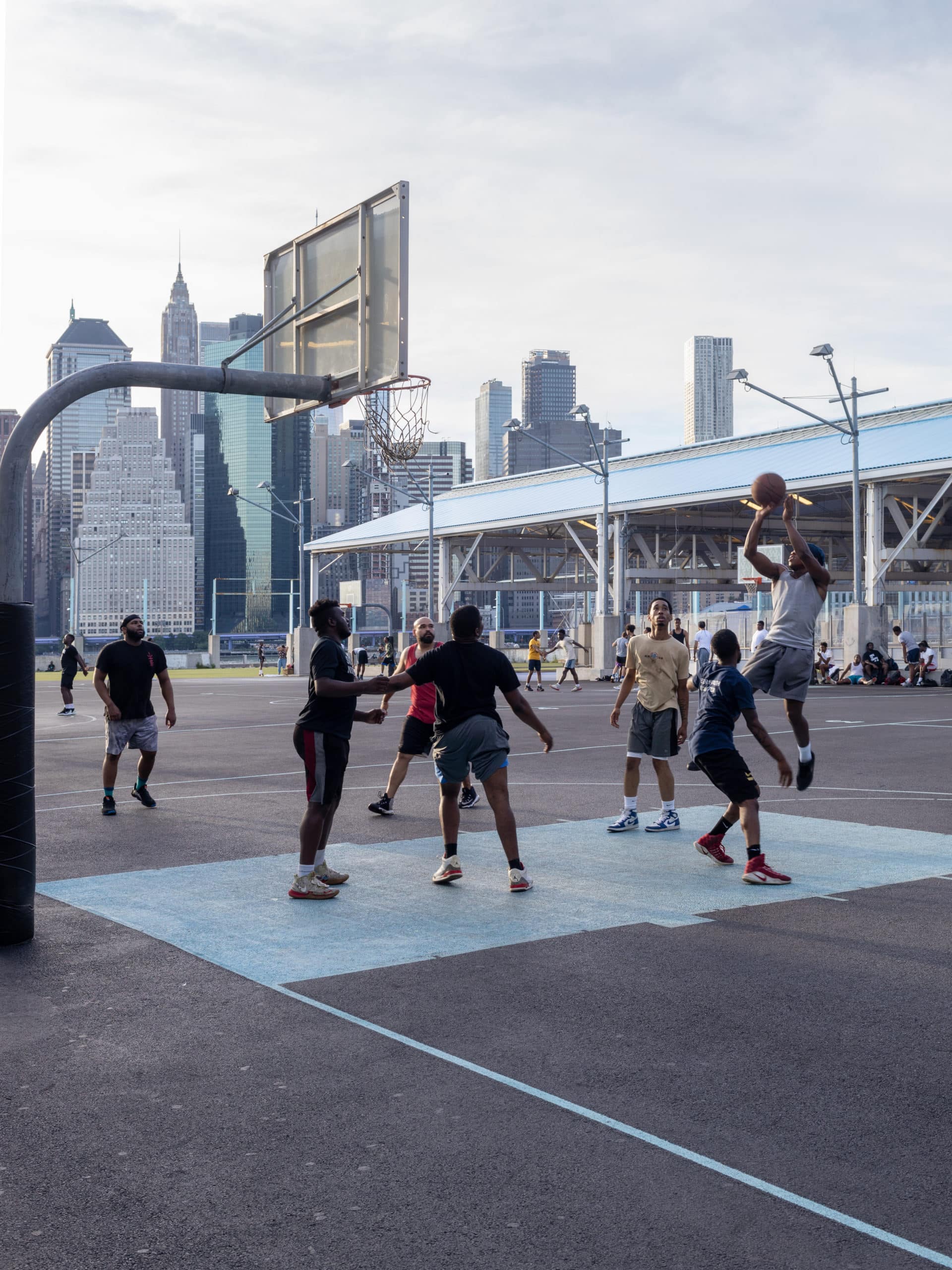 Young man shooting a basketball during a game on the courts at Pier 2.