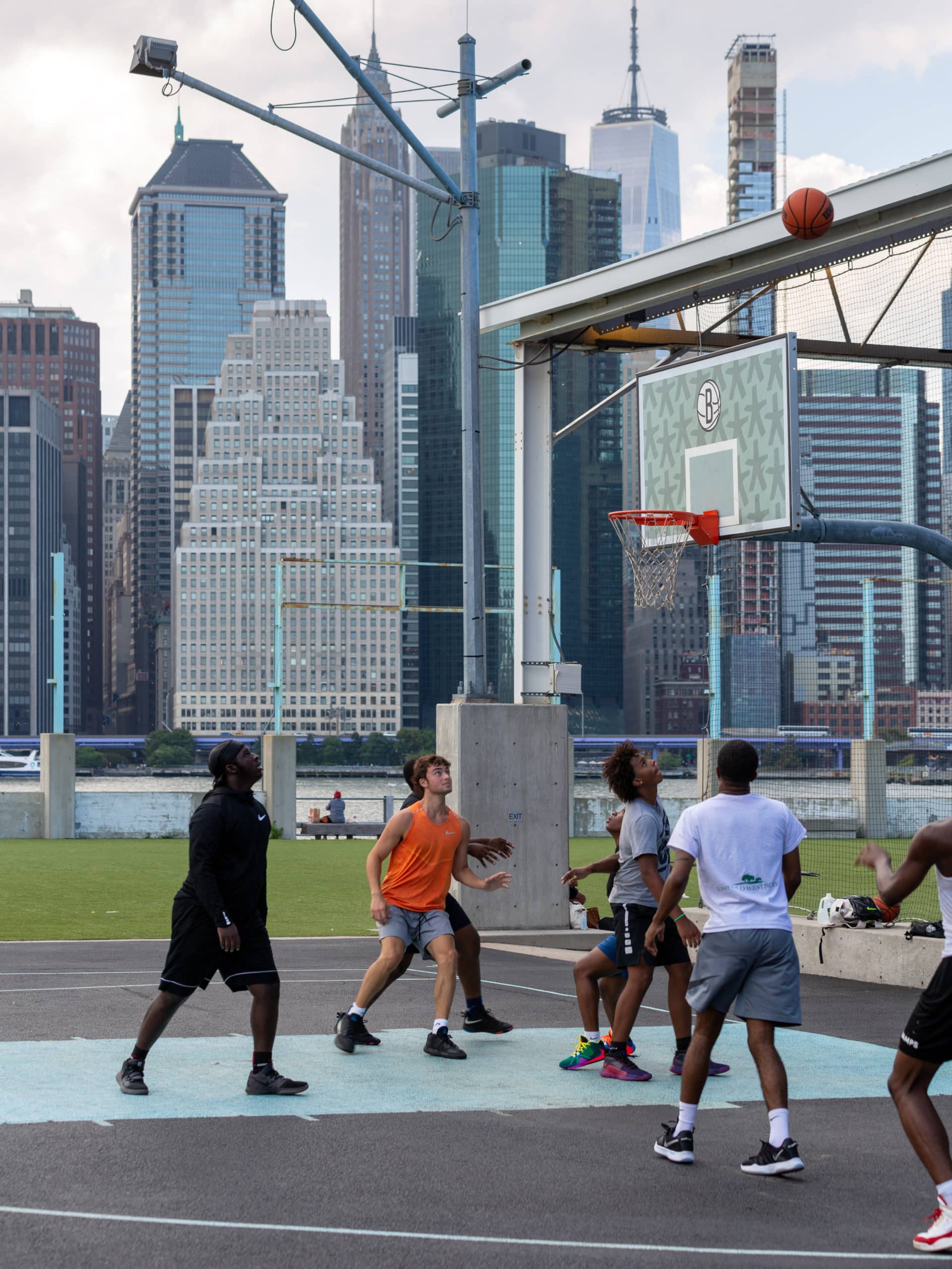 Players looking up at a basketball during a game on a court at Pier 2.
