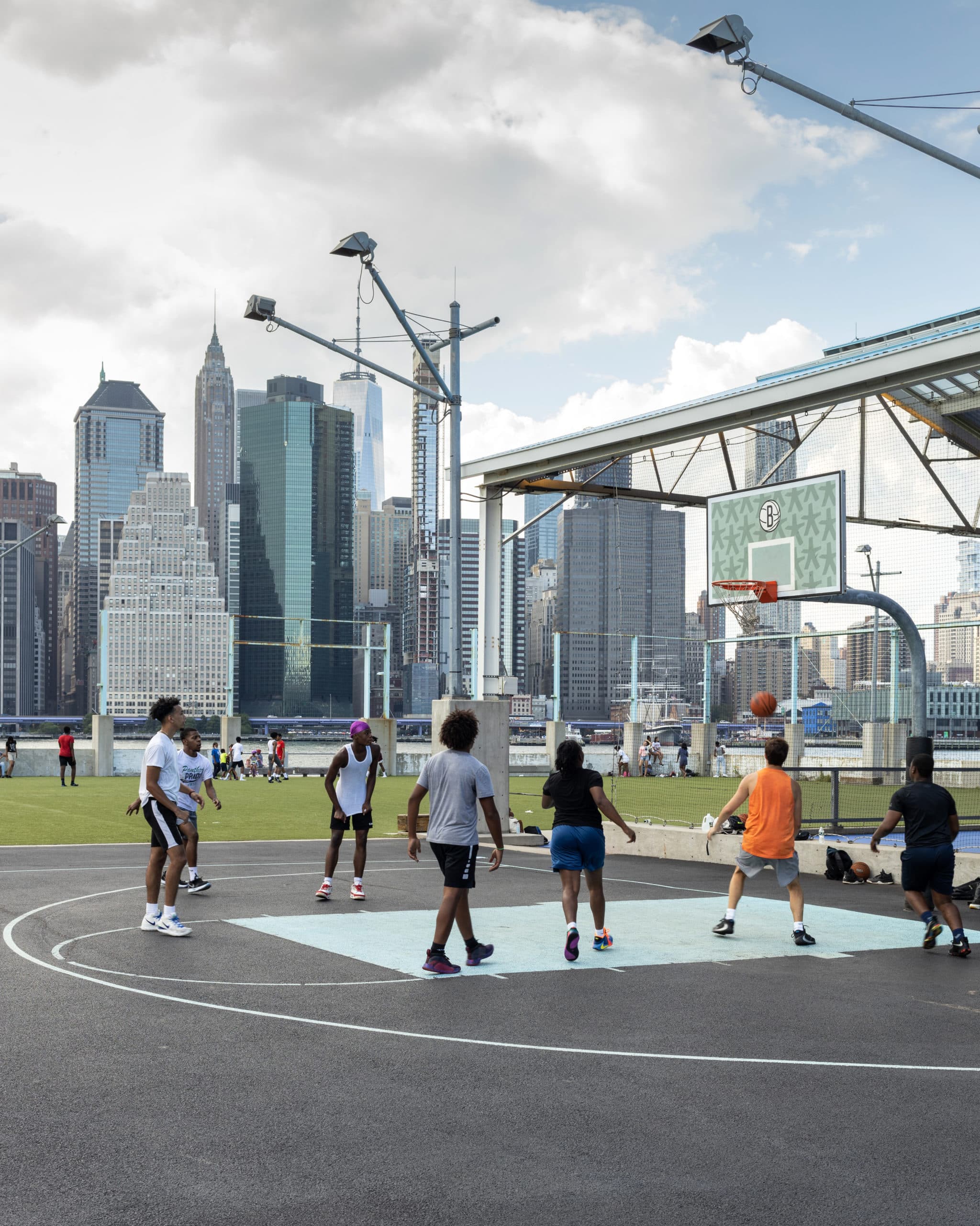 Group of people playing basketball at sunset on a court at Pier 2.