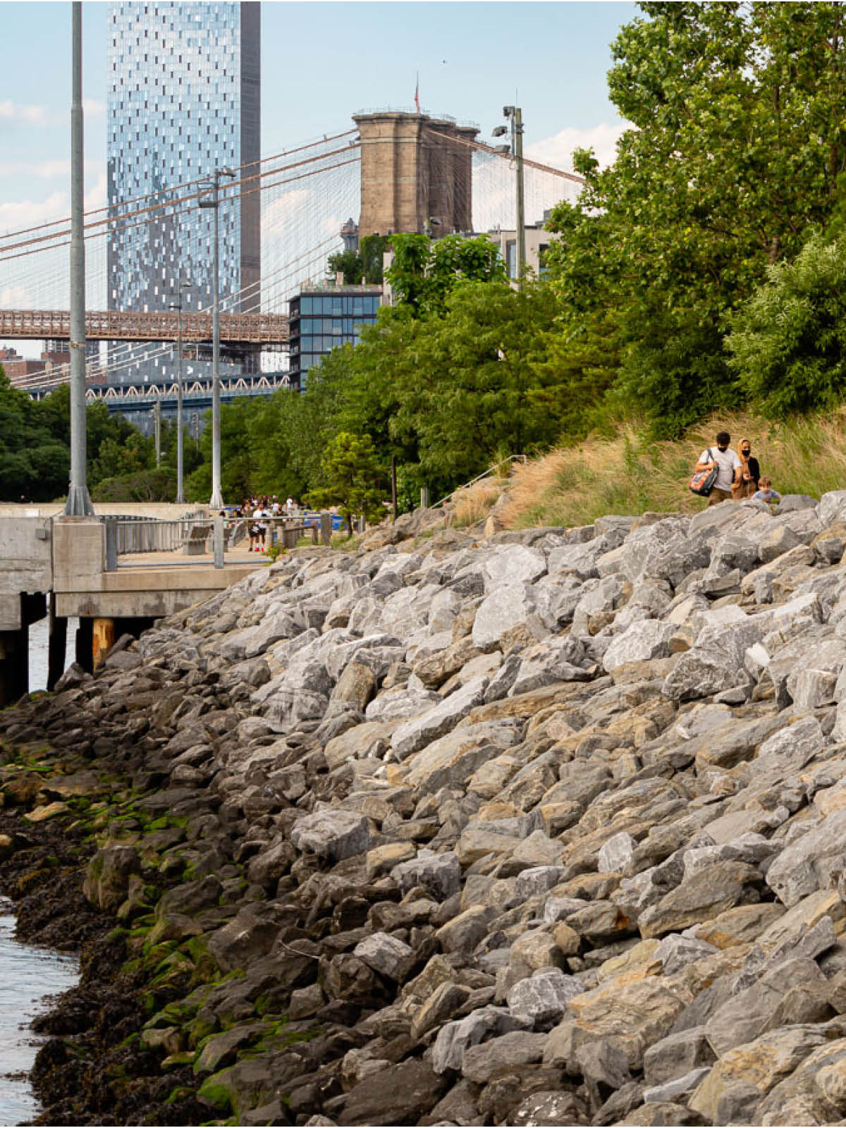 Rock barrier along the Pier 3 Greenway with the Brooklyn Bridge and One Manhattan Square in the distance.