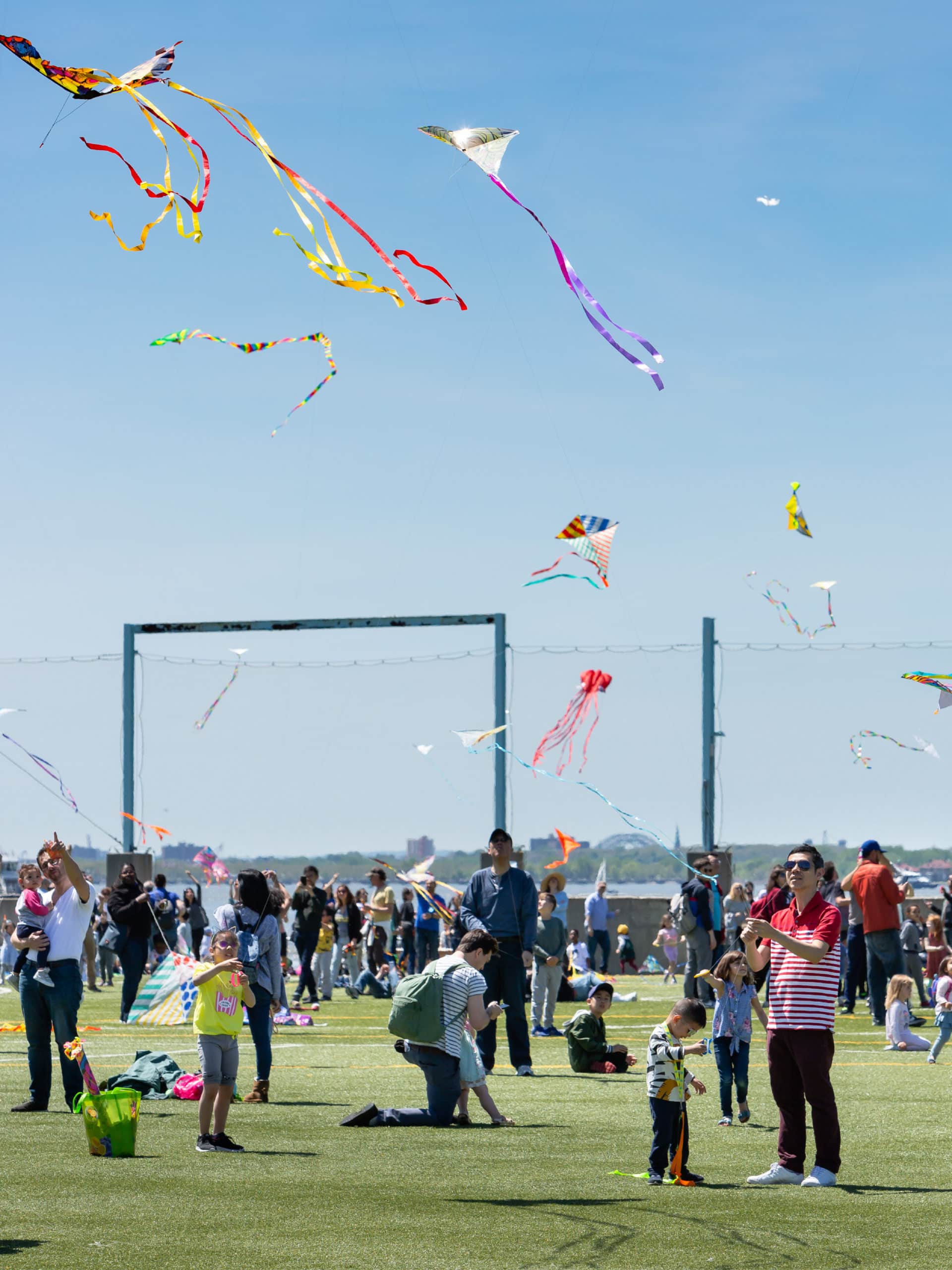 Crowd of people flying kites on a sunny day.