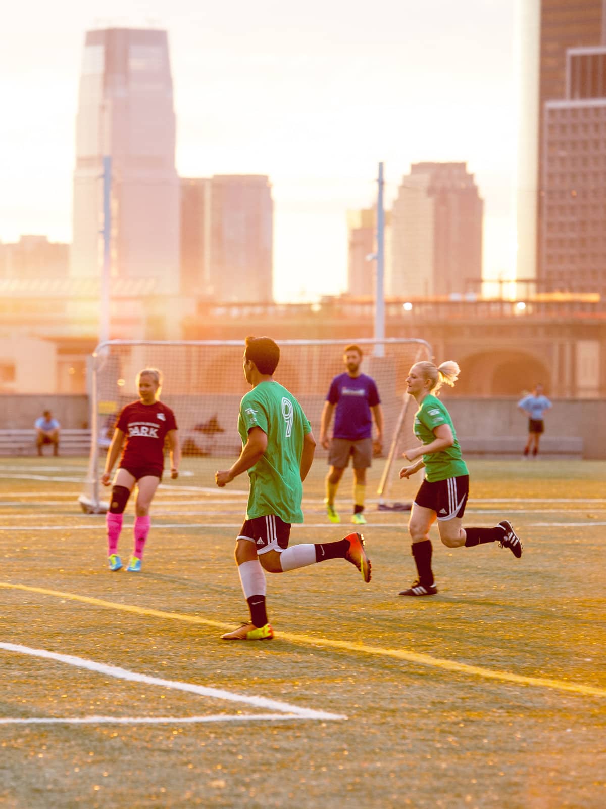 People playing soccer at sunset.