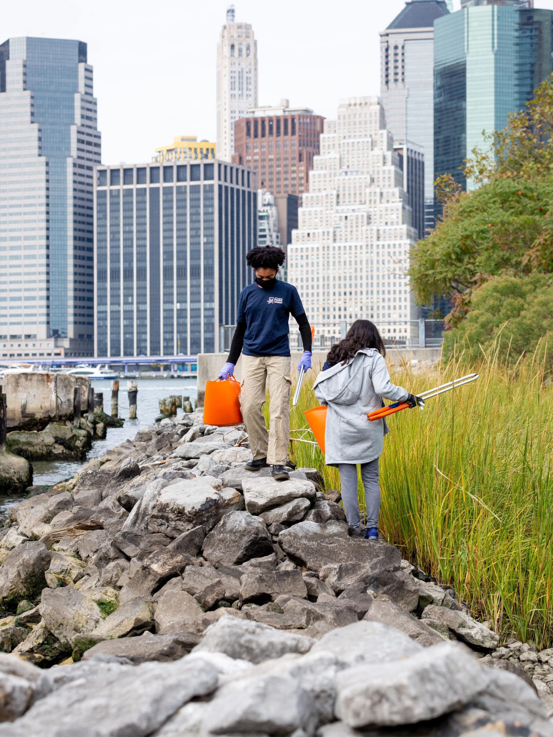 Teens cleaning up trash along the rocks by the Pier 1 Salt Marsh.