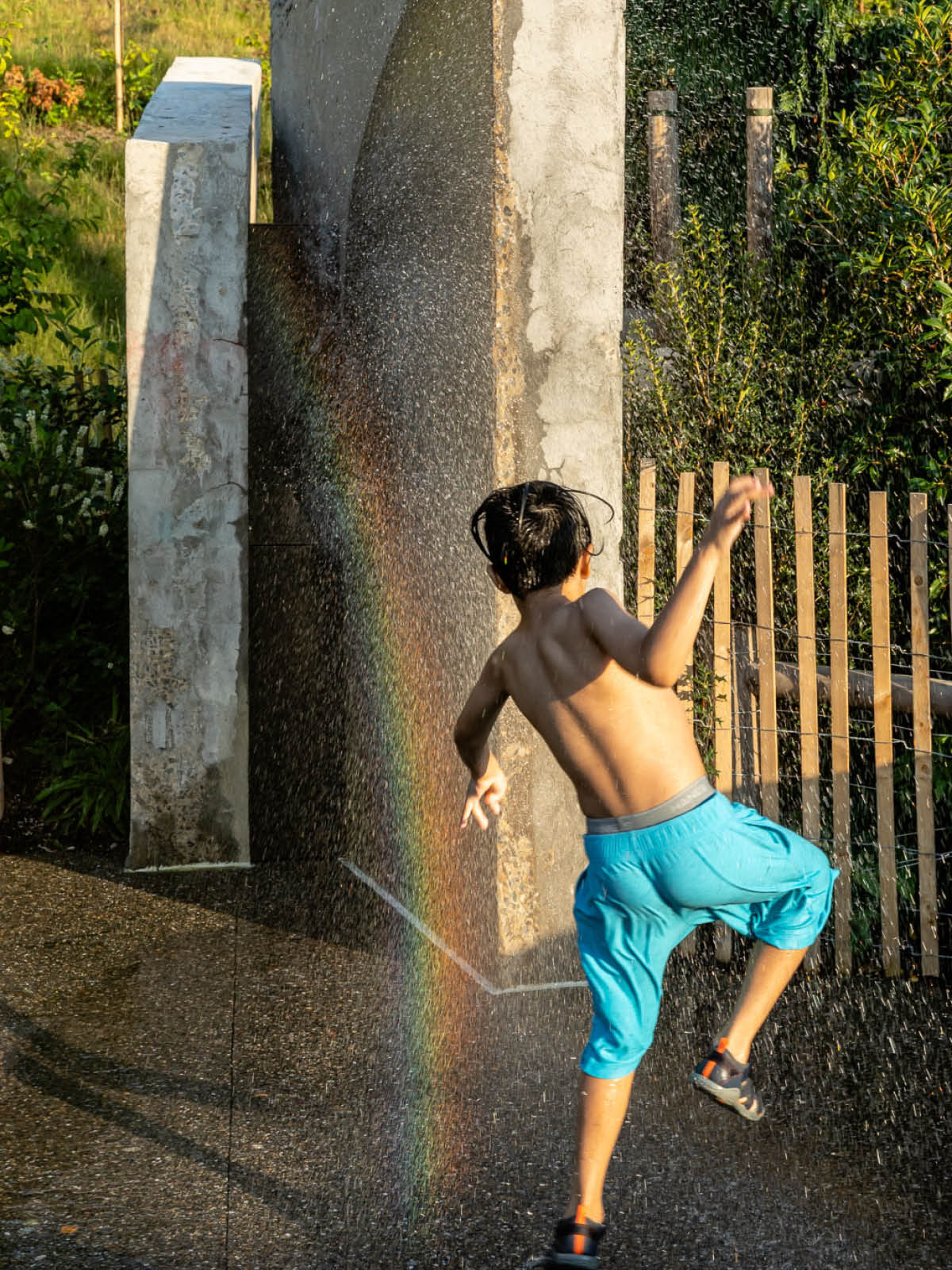 Young boy playing in the spray at a water area on a sunny day.