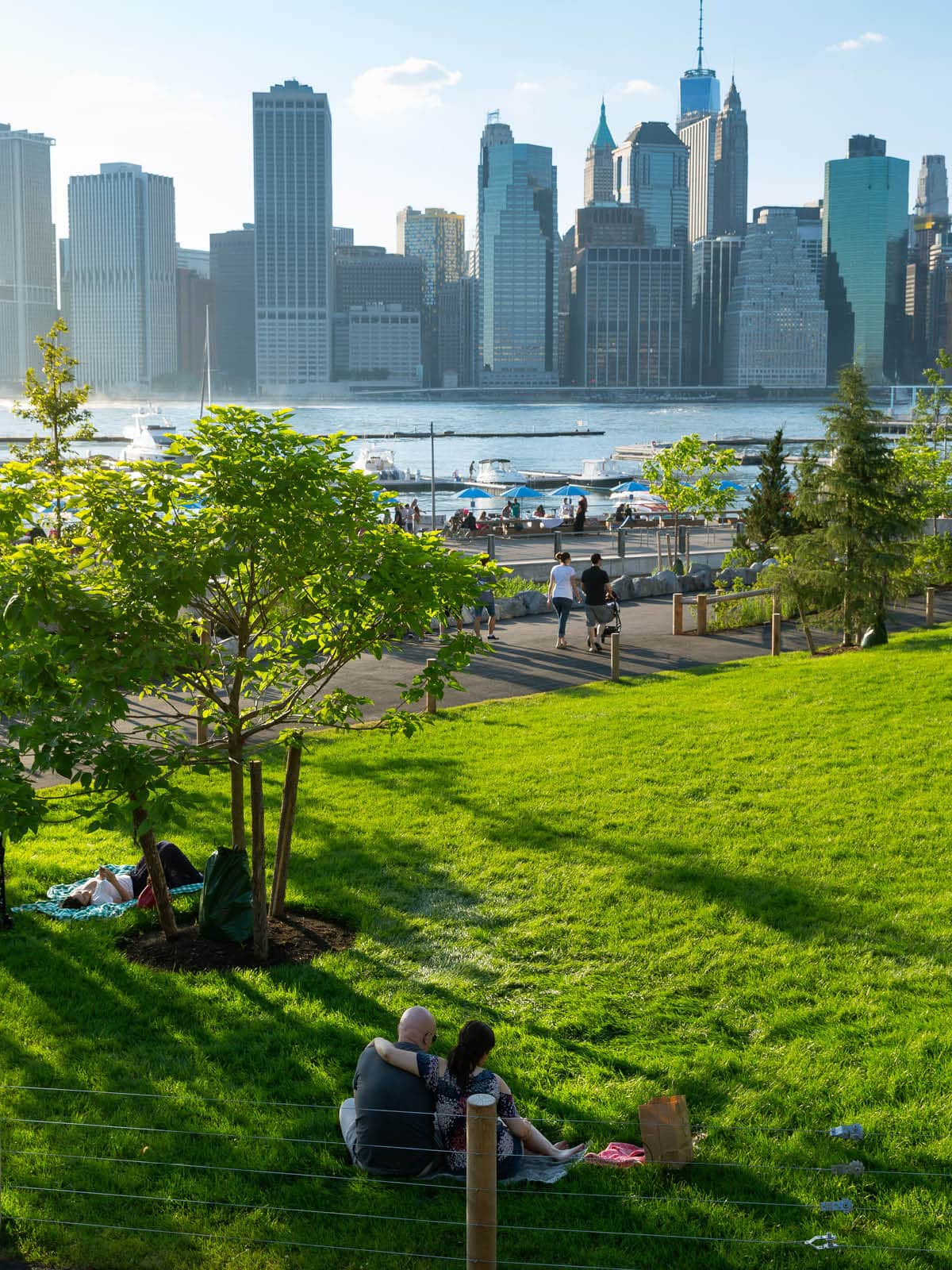 Couple sitting on the lawn with views of the water and lower Manhattan.