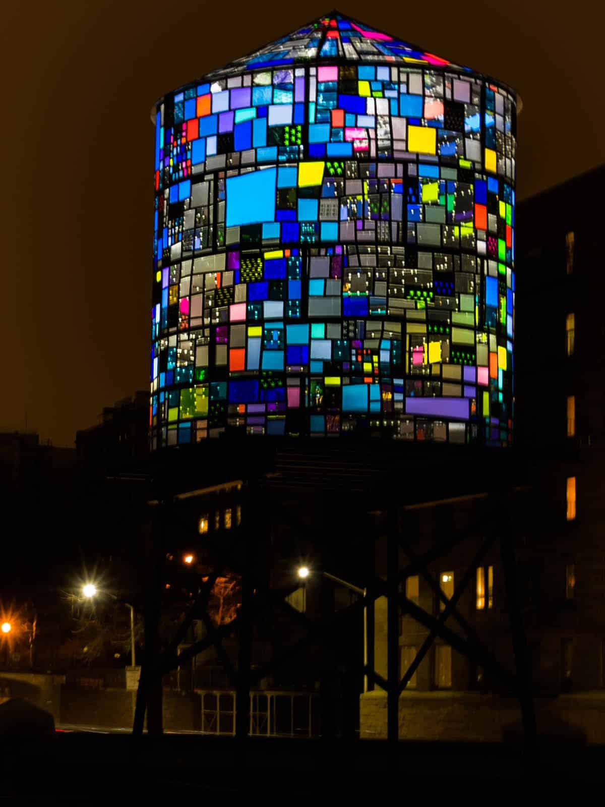View of Watertower II by Tom Fruin lit up at night. Sculpture is made from colored plexiglas and lit from within.