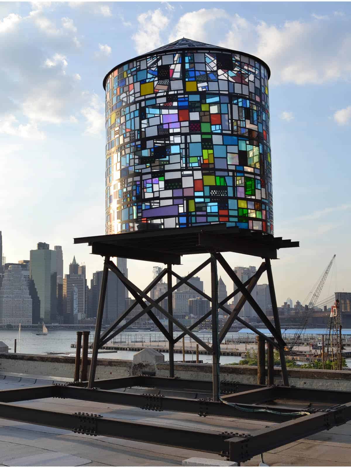 Watertower II by Tom Fruin, a colored plexiglas water tower seen on a sunny day with lower Manhattan in the background.