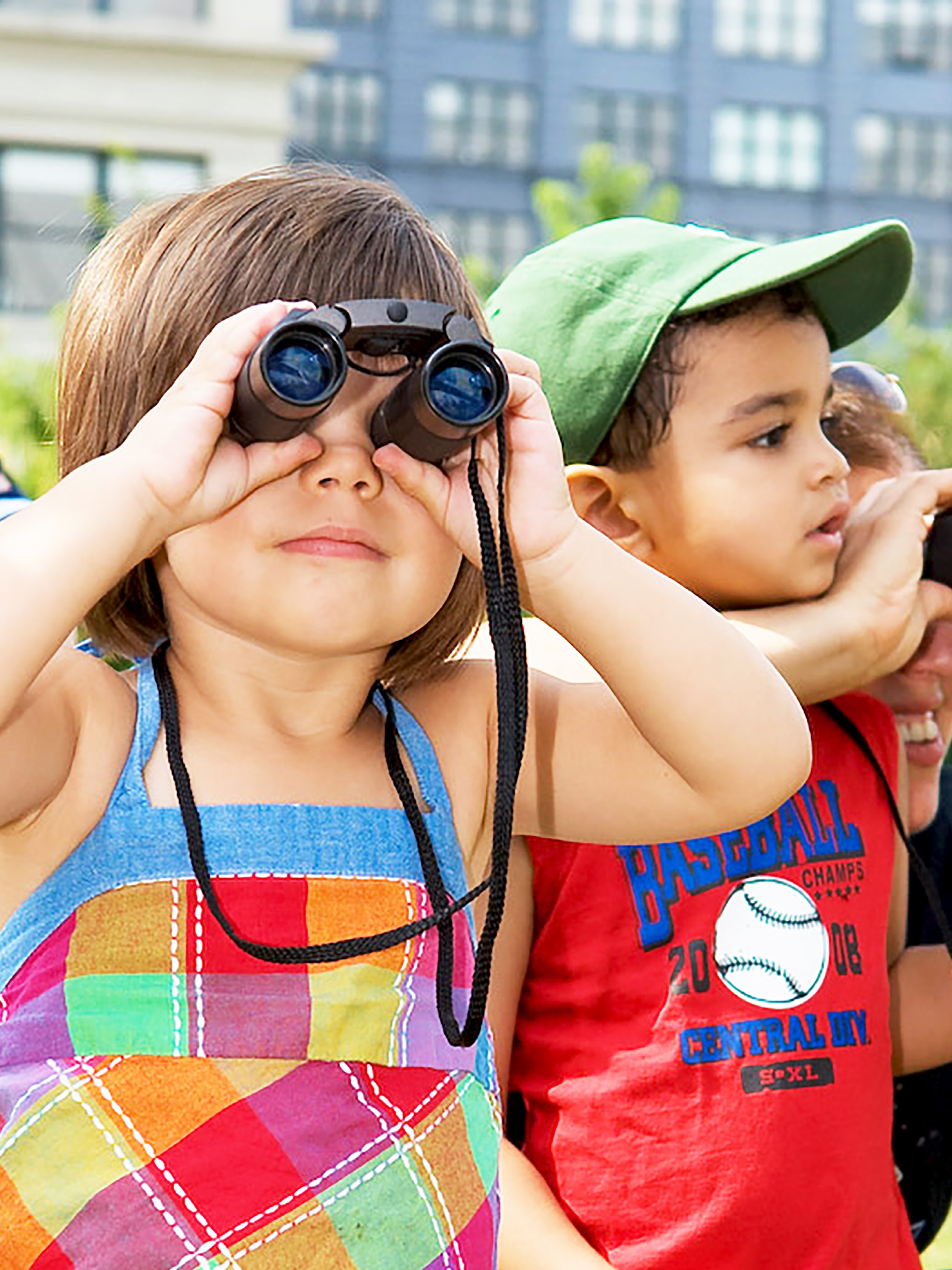 Small children looking through binoculars on a sunny day.