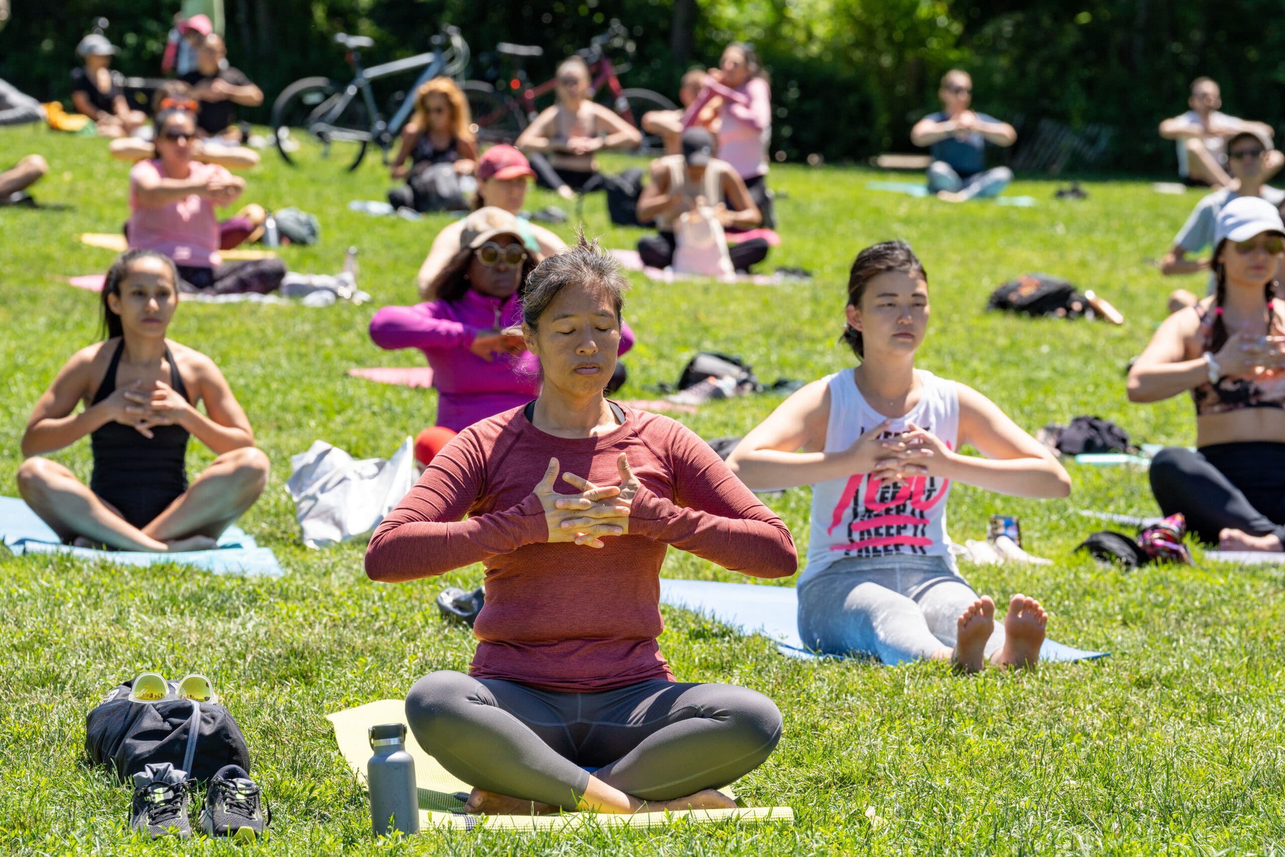 People practicing yoga on green grass, as part of International Day of Yoga 2022 in Brooklyn Bridge Park