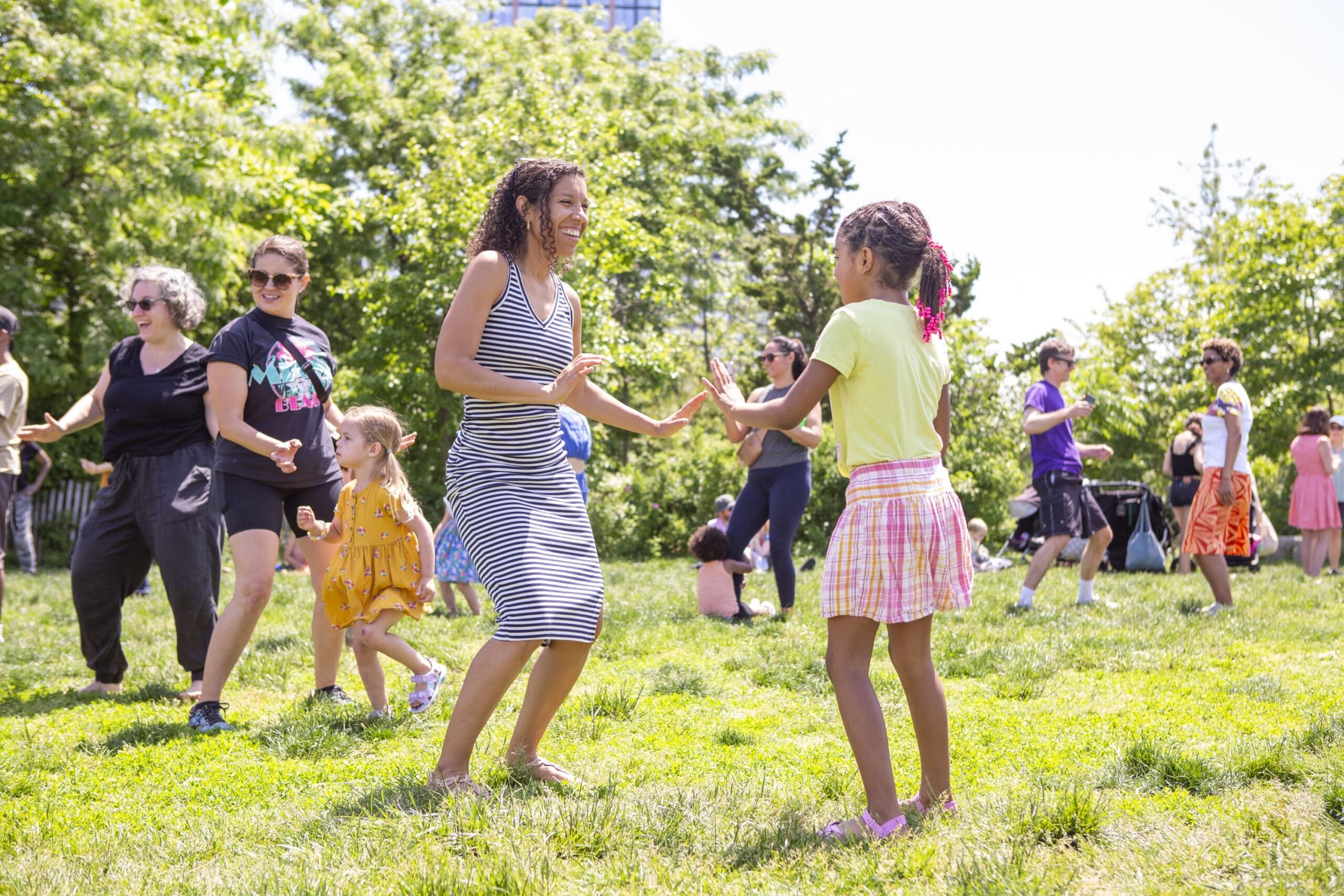 Children dancing on green grass at Brooklyn Bridge Park